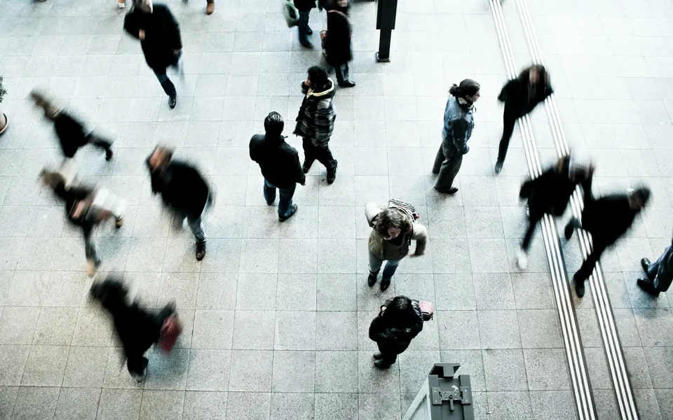 People moving across a busy station concourse, seen from above
